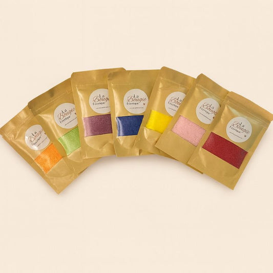Perles de Cire Décorative pour Bougie, avec ses différents coloris, orange, vert, violet, bleu, jaune, rose, blanc et rouge. Sur fond beige clair.