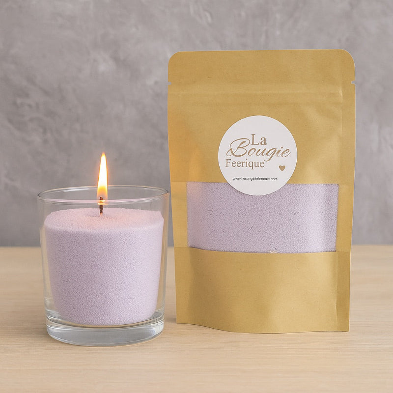 Perles de Cire Décorative DIY, de couleur violette, avec son contenant en verre et la bougie est allumée. Sur fond gris.