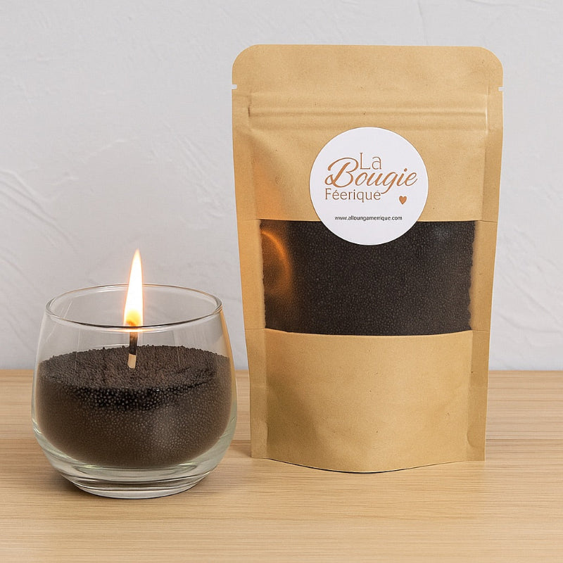 Perles de Cire Décorative DIY, de couleur noire et avec son contenant en verre, la bougie est allumée. Sur fond gris.