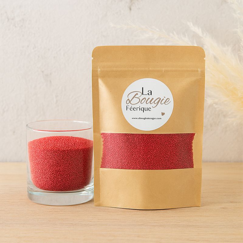 Recharge Bougie Cire Perle, de couleur rouge, avec son contenant transparent où il y a de la cire perle en démonstration. Fond beige.