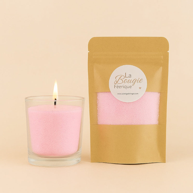 Recharge Bougie Cire Perle XL, Décorative DIY, de couleur rose et avec la cire perle dans un contenant en verre. La bougie est allumée. Fond beige clair.