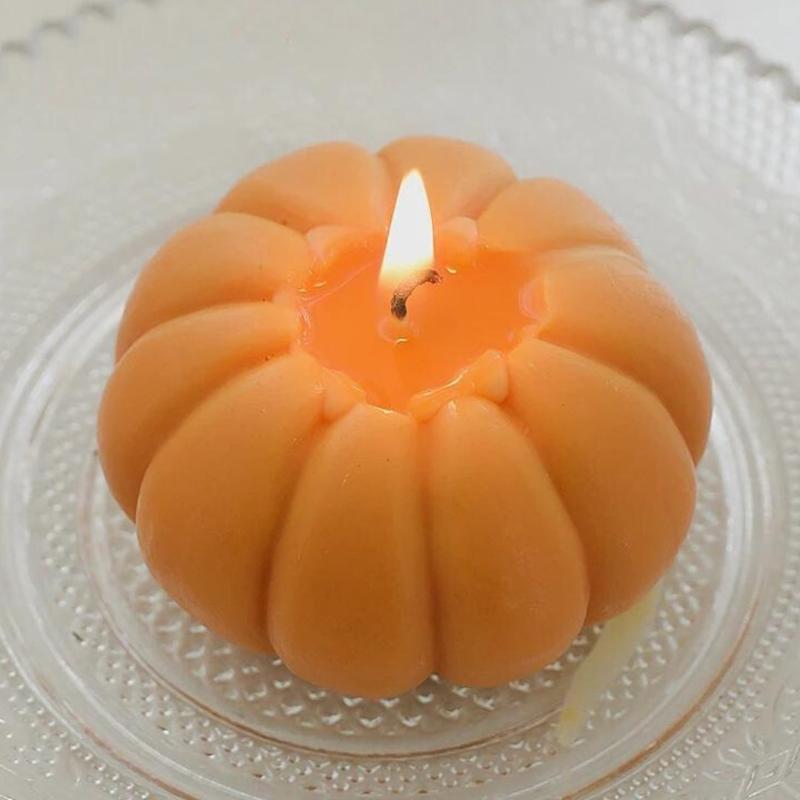 Bougie Décorative Fruit Citrouille, allumée et disposée dans une couple sur une table.